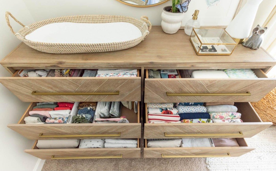 Commode à langer en bois, tiroirs ouverts avec bodies pliés et organisés
